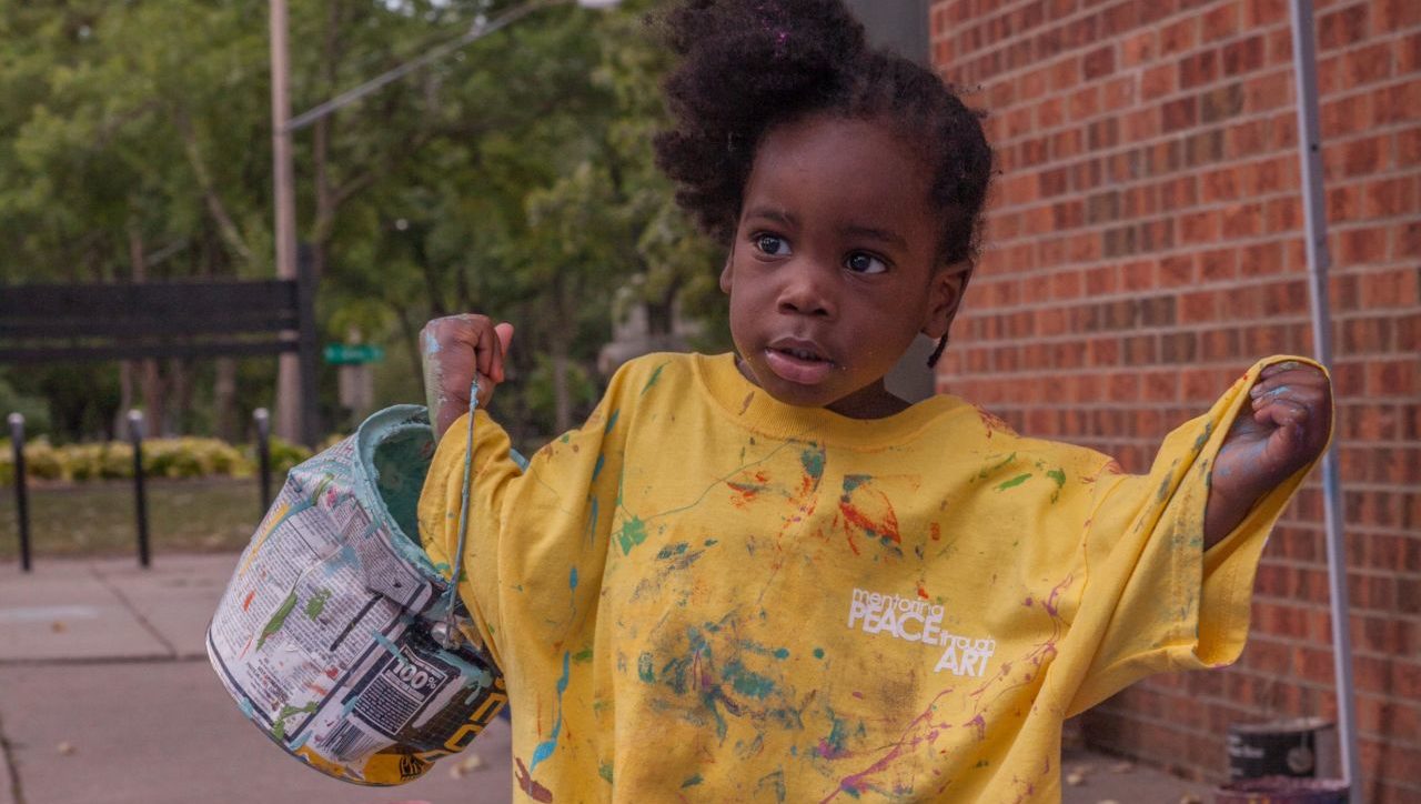 Girl in yellow shirt carrying paint can